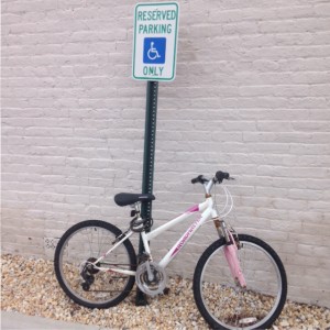 bike chained to sign reading, "reserved parking handicapped only"