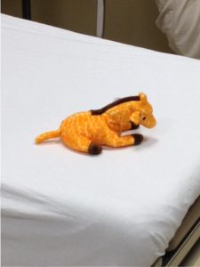 A child's stuffed toy in shape of giraffe on hospital exam table