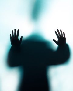 silhouette of person pushing against glass